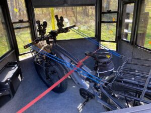 An electric bicycle is secured with red and blue straps inside a portable hunting blind.